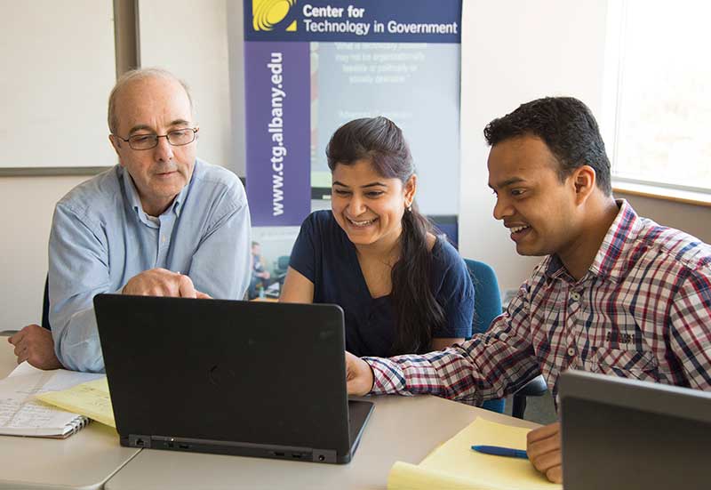 Three researchers working together on a computer at the Center for Technology in Government.