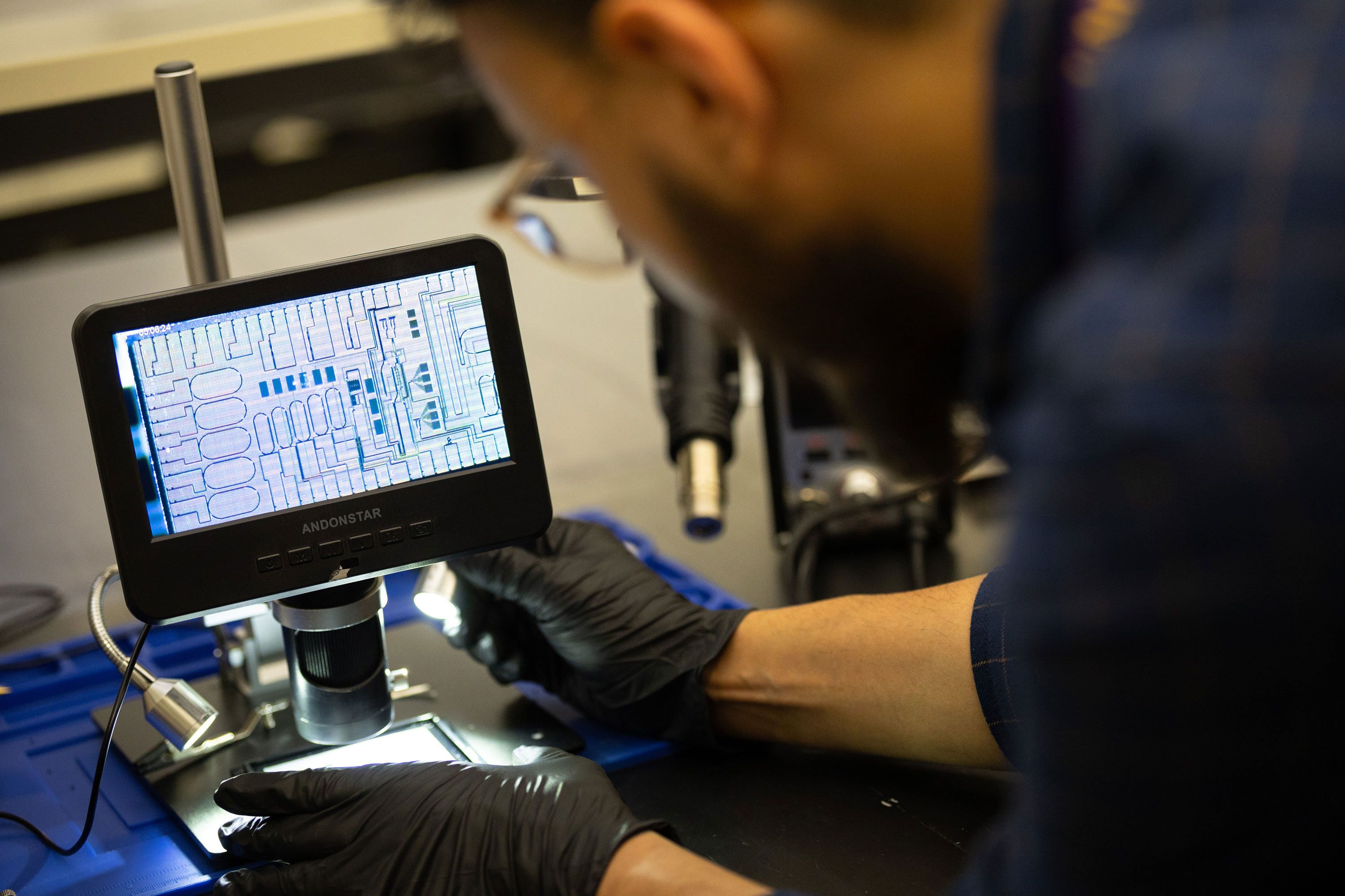 A researcher wearing black gloves adjusts a piece of equipment inside the quantum photonic measurement lab.