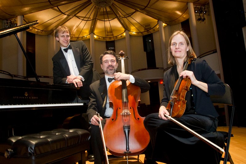 a pianist, cellist and violinist pose with their instruments