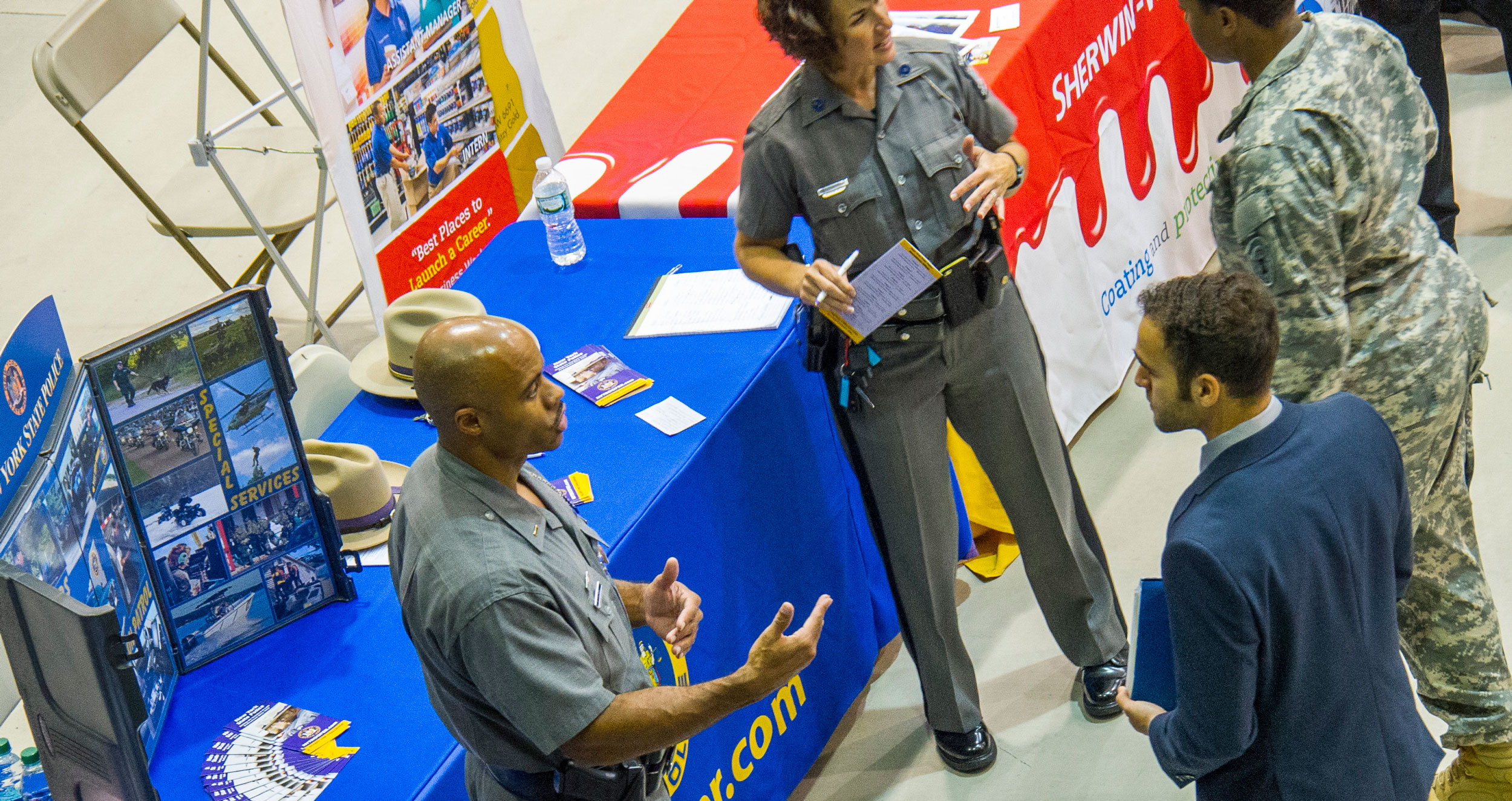 Members of the New York State Police speak with two students at a career fair.