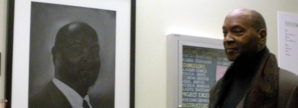 Dr. Carson Carr (Former Director of UAlbany EOP program) standing next to self-portrait 