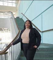 Student standing on stairs leaning on rail in lower level of Massry.