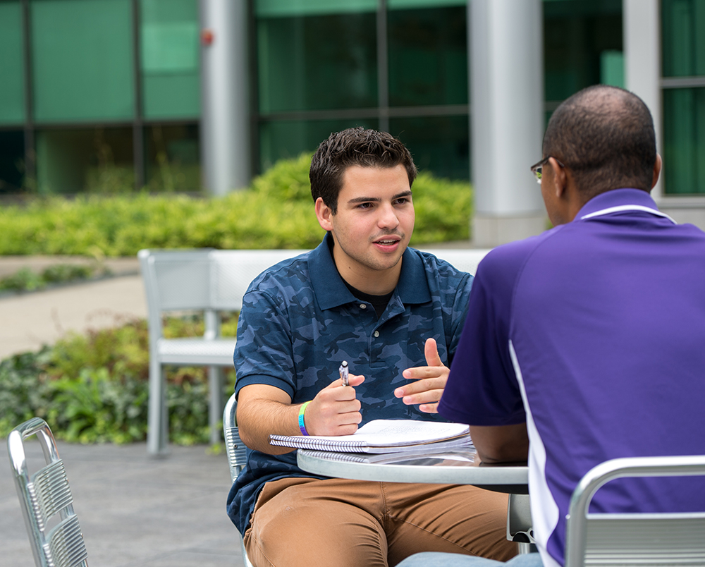 Two people having a discussion in the UAlbany Life Sciences courtyard