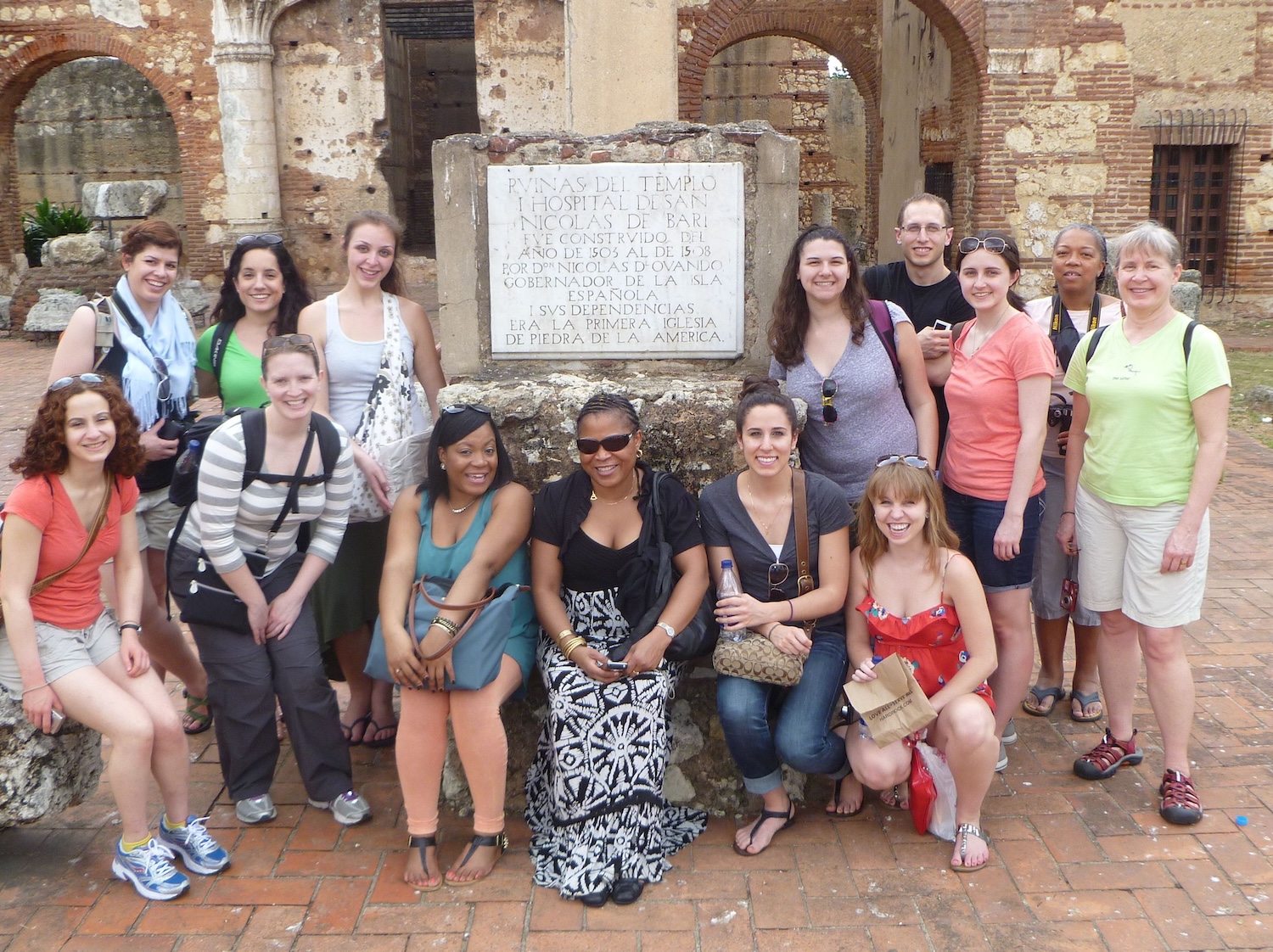 Students stand around a sign in the Dominican Republic, smiling at the camera.