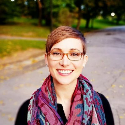 person smiling in colorful scarf and glasses outside