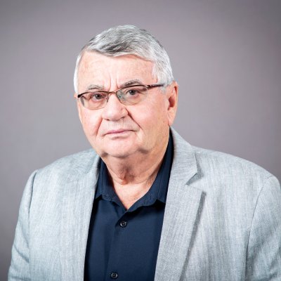 portrait of a person in glasses black shirt and gray suit jacket