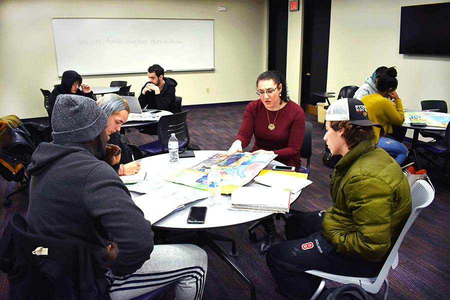 Rae Muhlstock (center) discusses posters made by middle school students with her class.