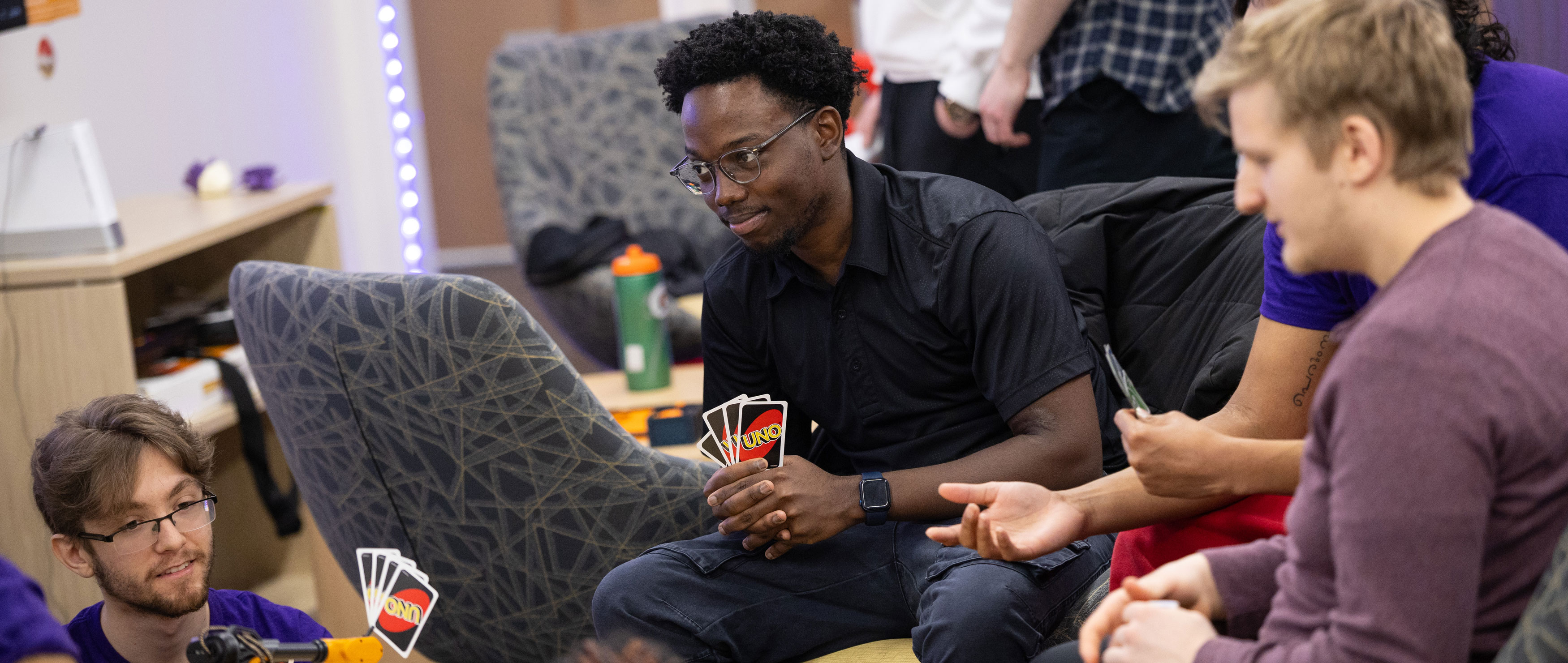 A group of students plays the card game Uno inside the ETEC game room.