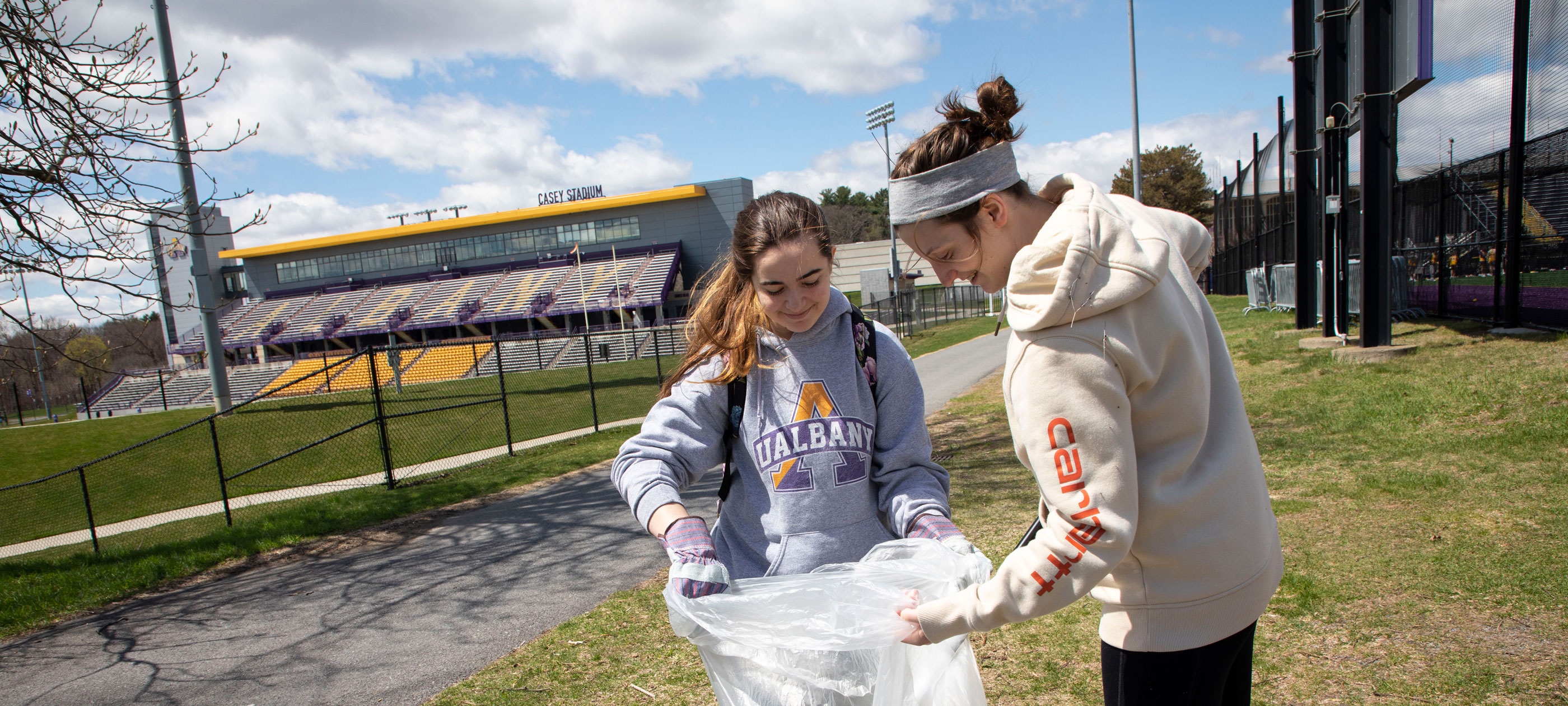 Two students collect litter on UAlbany's Uptown Campus for Earth Day.