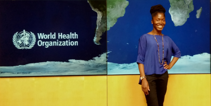 A student stands next to a wall that has "World Health Organization" printed on it