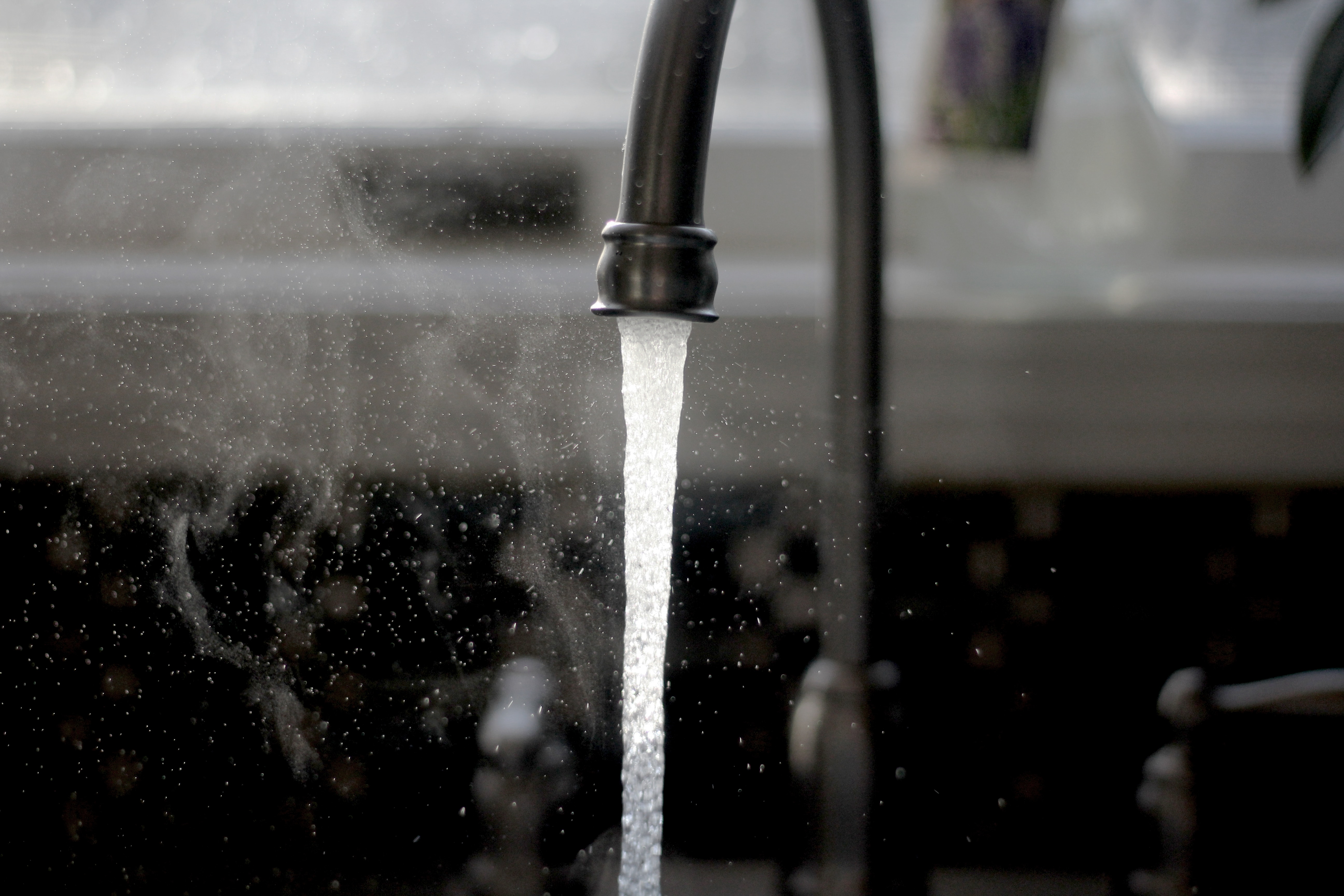 Close up of kitchen faucet with a strong stream of water