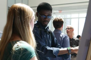 Fred Boakye Oppong providing feedback to a student at the 2025 REU Summer Program Poster Presentation