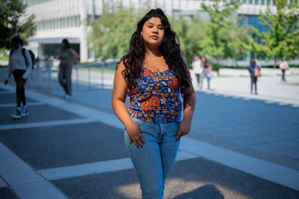 Gabriela A. Cruz Hernandez, in a flowered shirt and heans, walks toward the camera