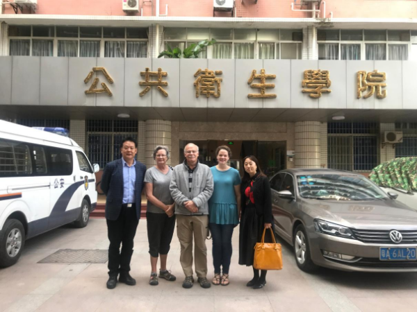 Researcher Gus Birkhead stands in front of a building in China with colleagues.