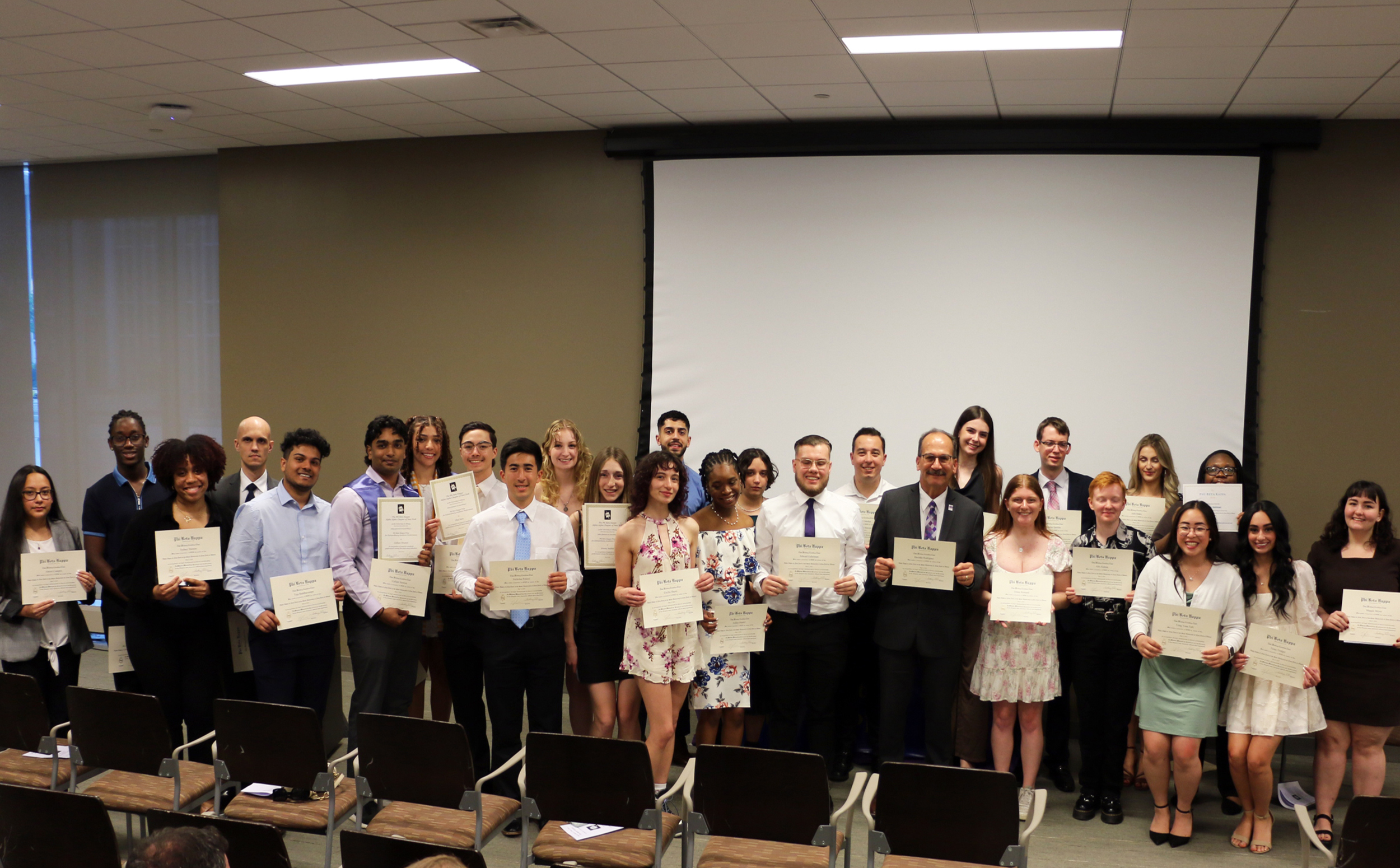 UAlbany's 2024 inductees into the Phi Beta Kappa society show their certificates with special inductee President Havidan Rodriguez.