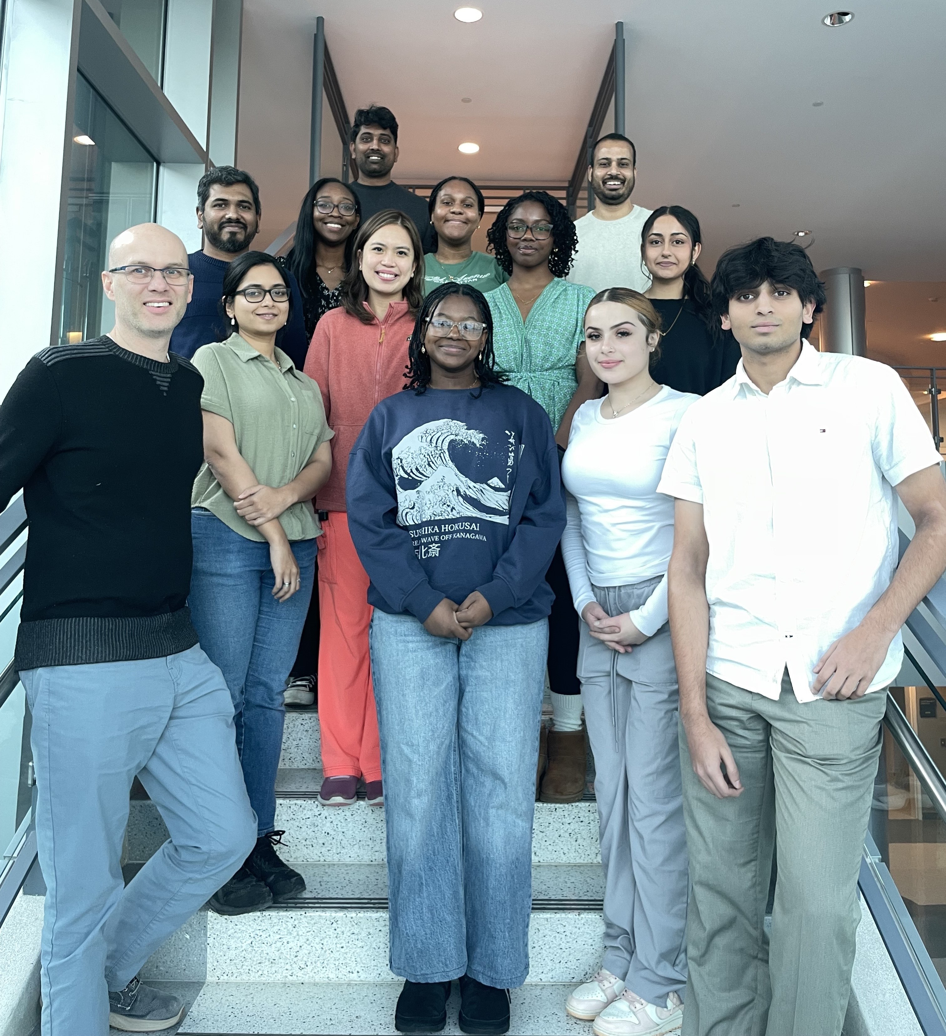 Group portrait of the Halvorsen lab. The smiling group includes 8 women and 5 men standing in a brightly lit stairwell.