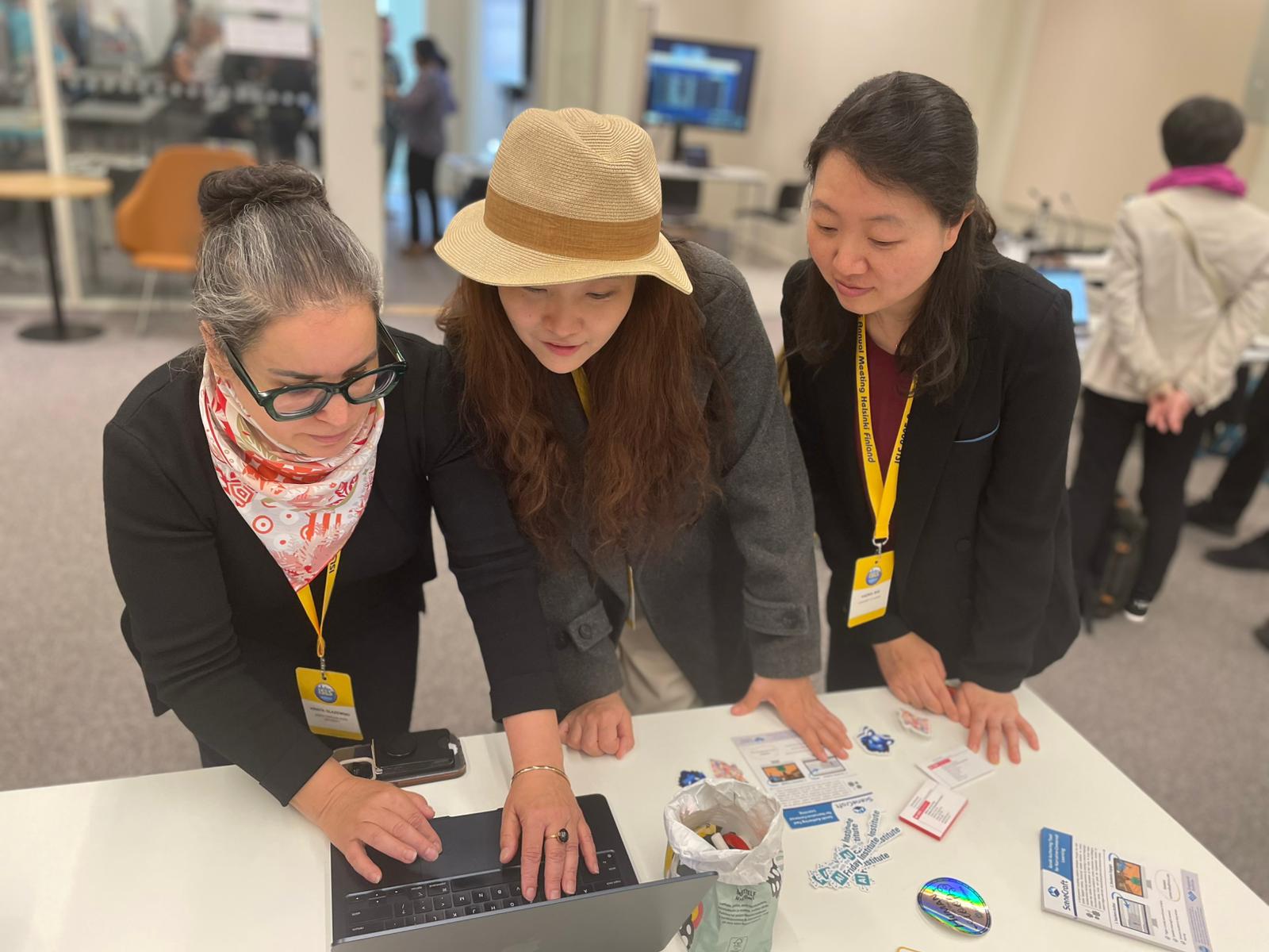 three individuals looking at a laptop