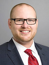 A smiling young man in blue suit and red tie
