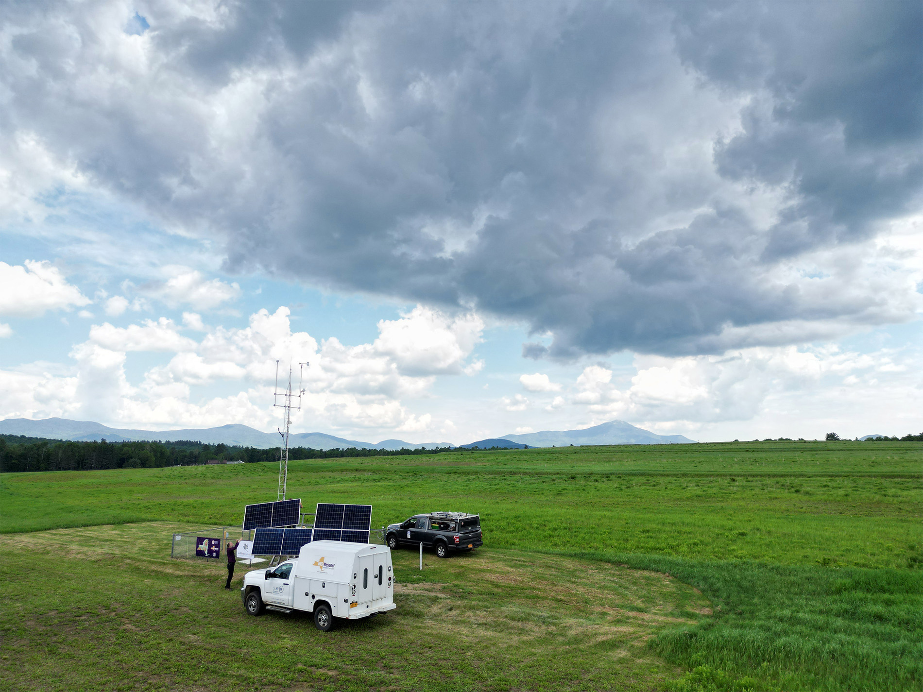 A drone image offers an ariel view of the Mesonet site in Lake Placid with the Adirondack Mountains behind it.