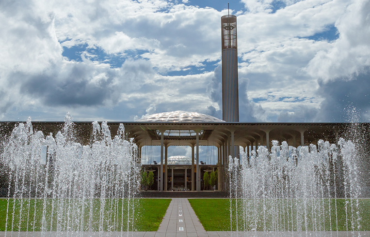 Fountains flow on campus in front of the UAlbany Academic Podium on a cloudy day.