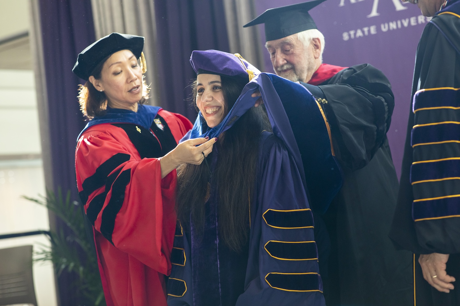 An environmental health sciences student receives her hood at graduation.