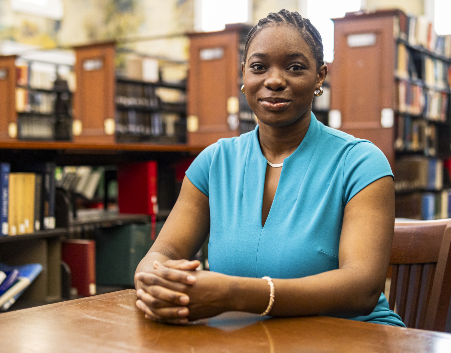 a woman in a blue shirt sits in a library