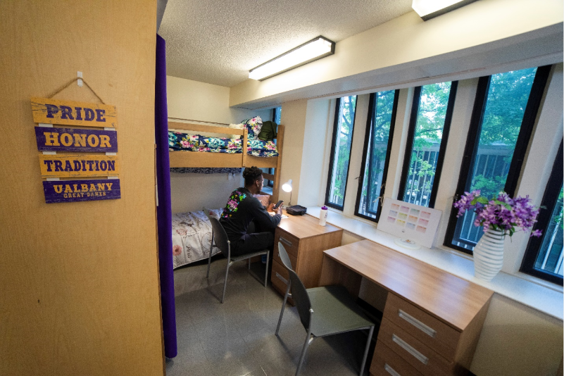 A student sits at a desk in a UAlbany dorm room