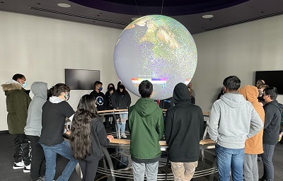Rise High students stand around the projector globe in the science-on-a-sphere room.