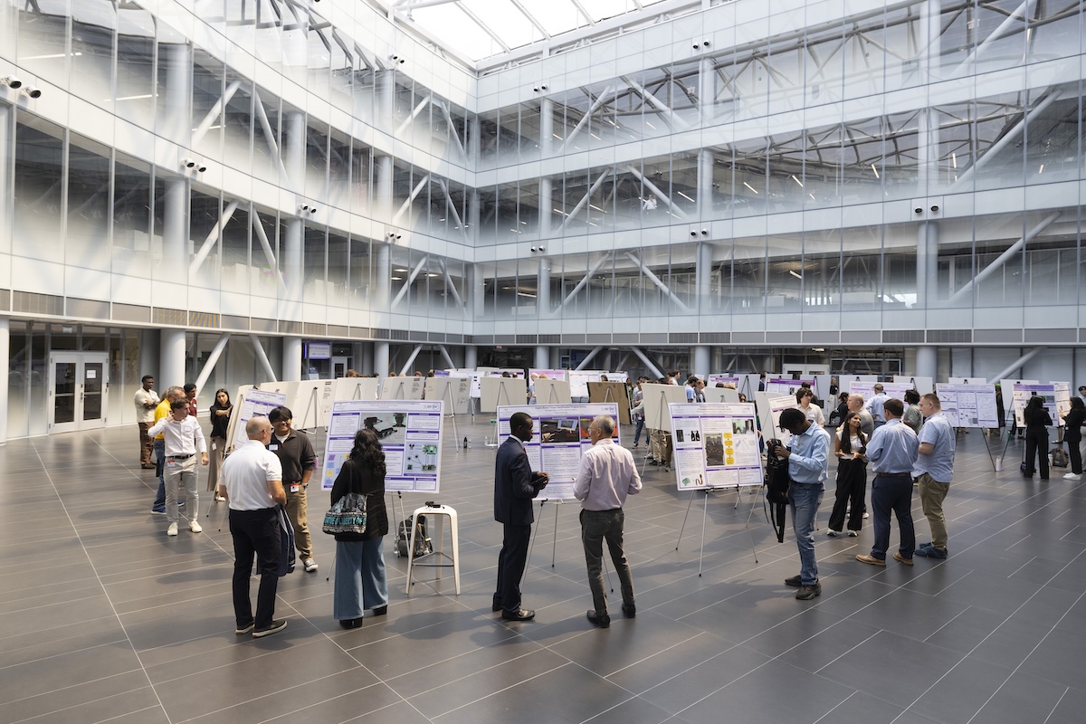 People stand around research posters inside a large spacious building