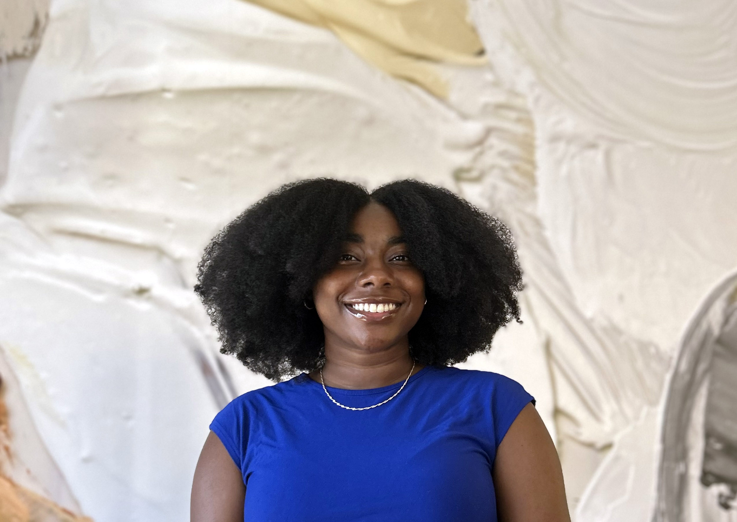 A potrait of UAlbany graduate Sanaa Woodley in front of a mural