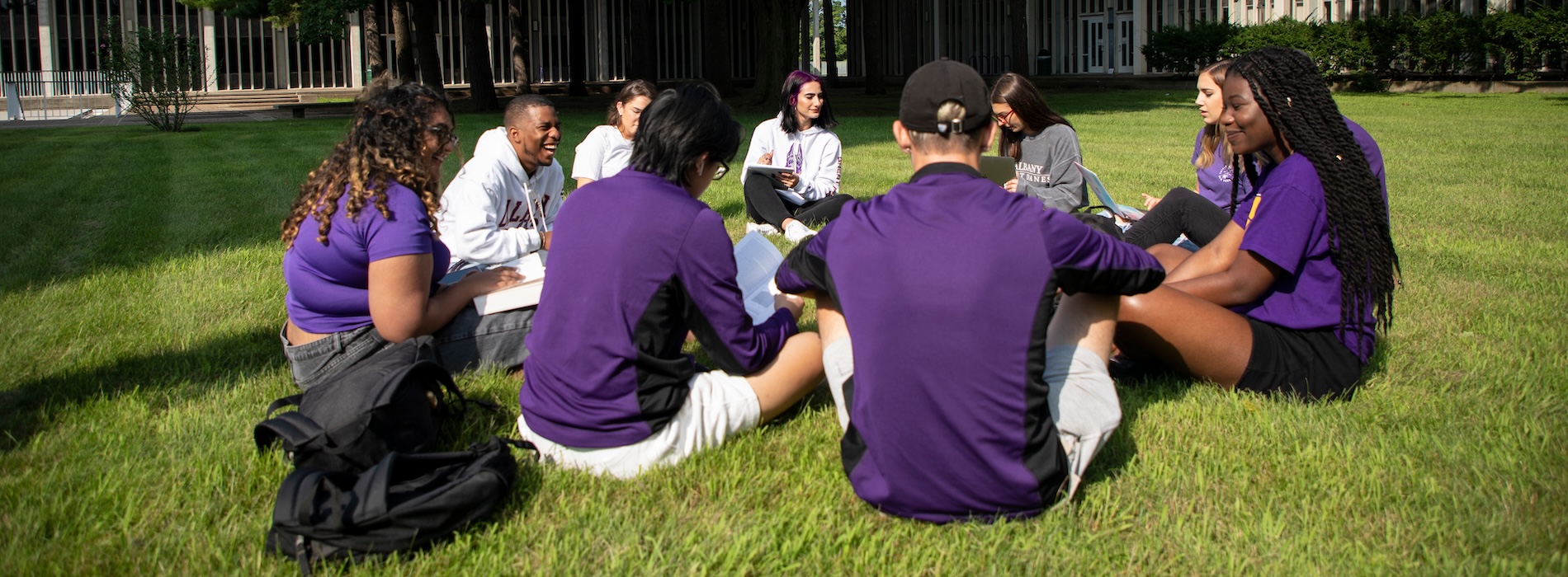Students sitting in circle outside on lawn