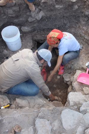 Veronica Perez Rodriguez wears a red bandana as she crouches while excavating a burial at the site of Cerro Jazmin, Oaxaca.