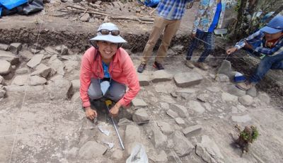 Veronica Perez Rodriguez, in a white hat and coral shirt, smiles while she works on an excavation at the Mixtec site of Cerro Jazmin in Oaxaca, Mexico.