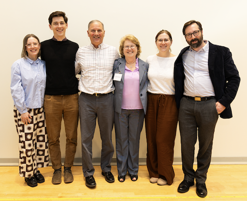 Six smiling people stand and pose for a photo