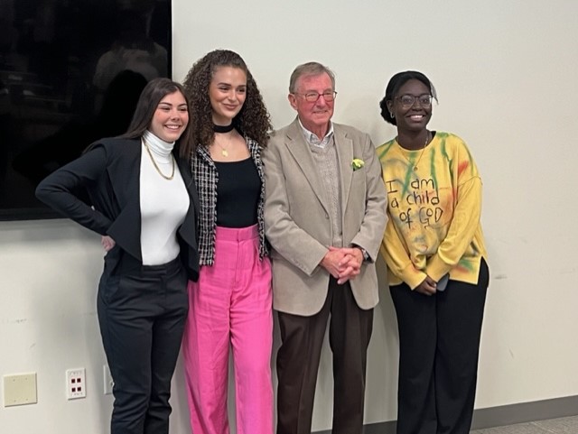 Three women pose next to Professor Ray Van Ness for a photo