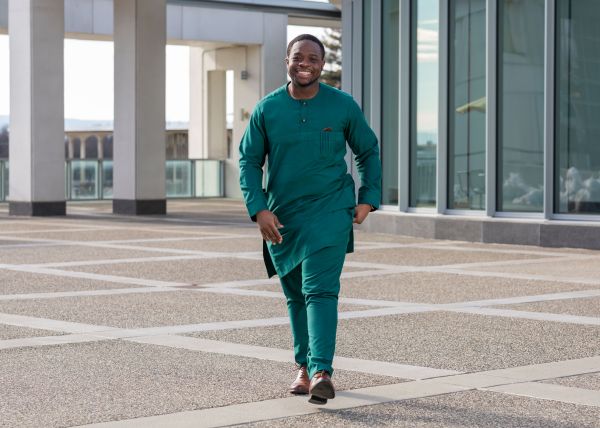 T’Oluwanimi Ademola-Thomas, in green tunic and pants, walks across the Podium