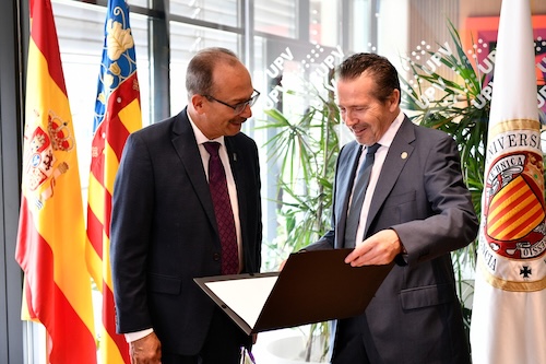 Two men in business suits stare at a folder in a brightly lit room with a flag behind them