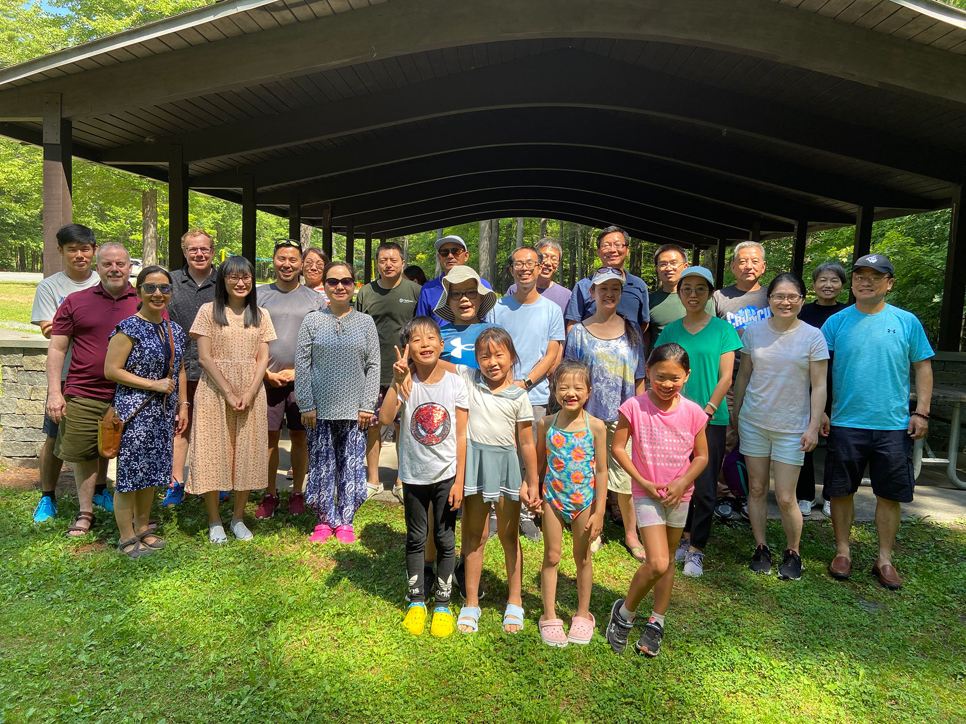 The UAlbany Asian Coalition of Professionals gather for a group photo in front of an outdoor pavilion