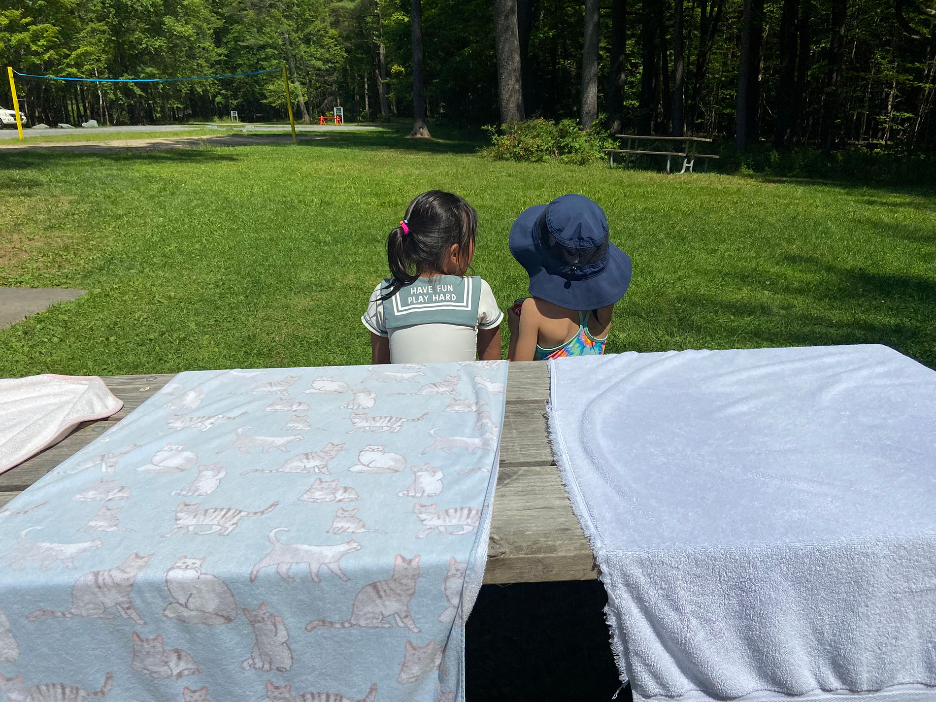 Two children are sitting together on a bench outside