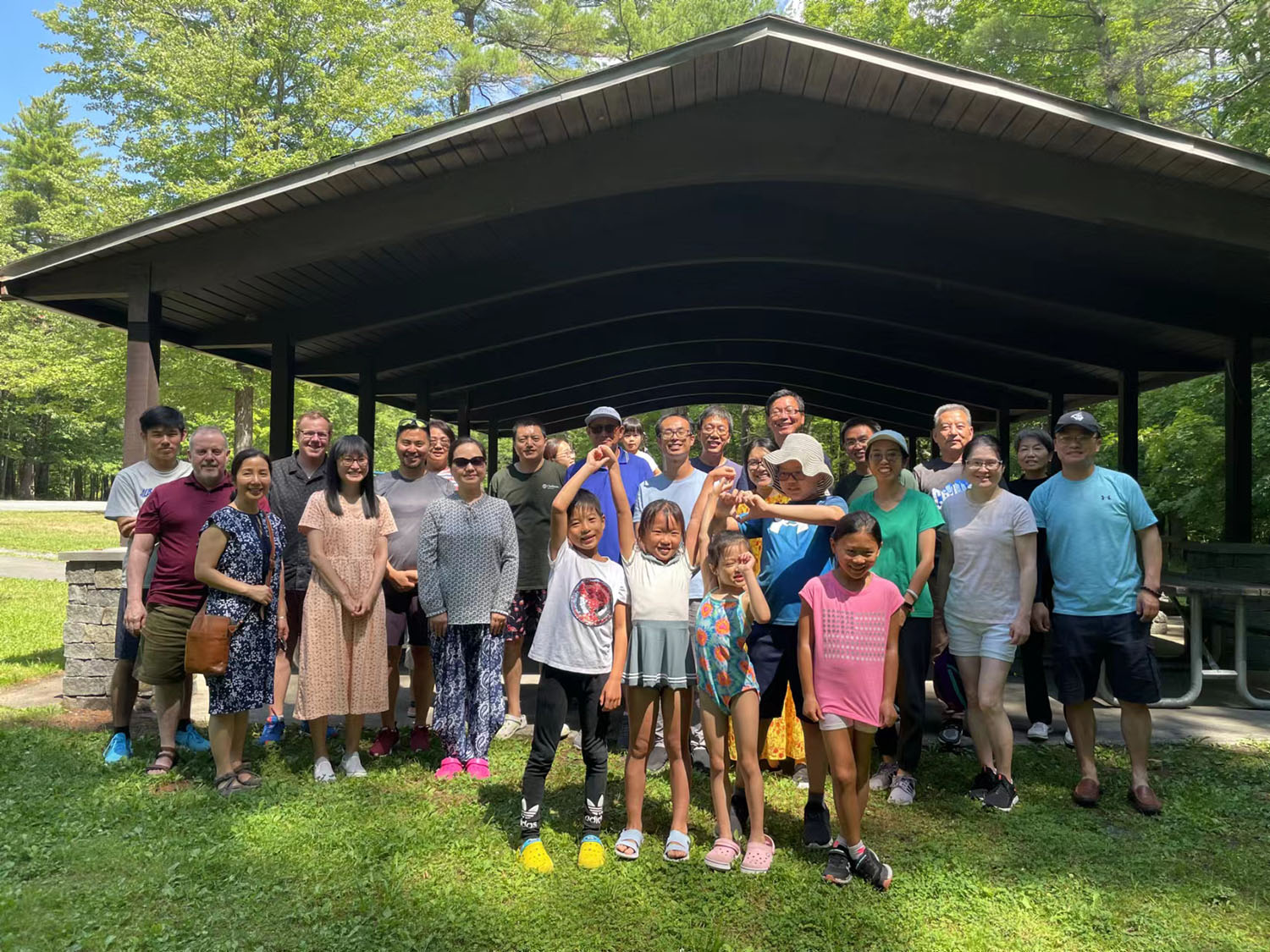 The UAlbany Asian Coalition of Professionals gather for a group photo in front of an outdoor pavilion