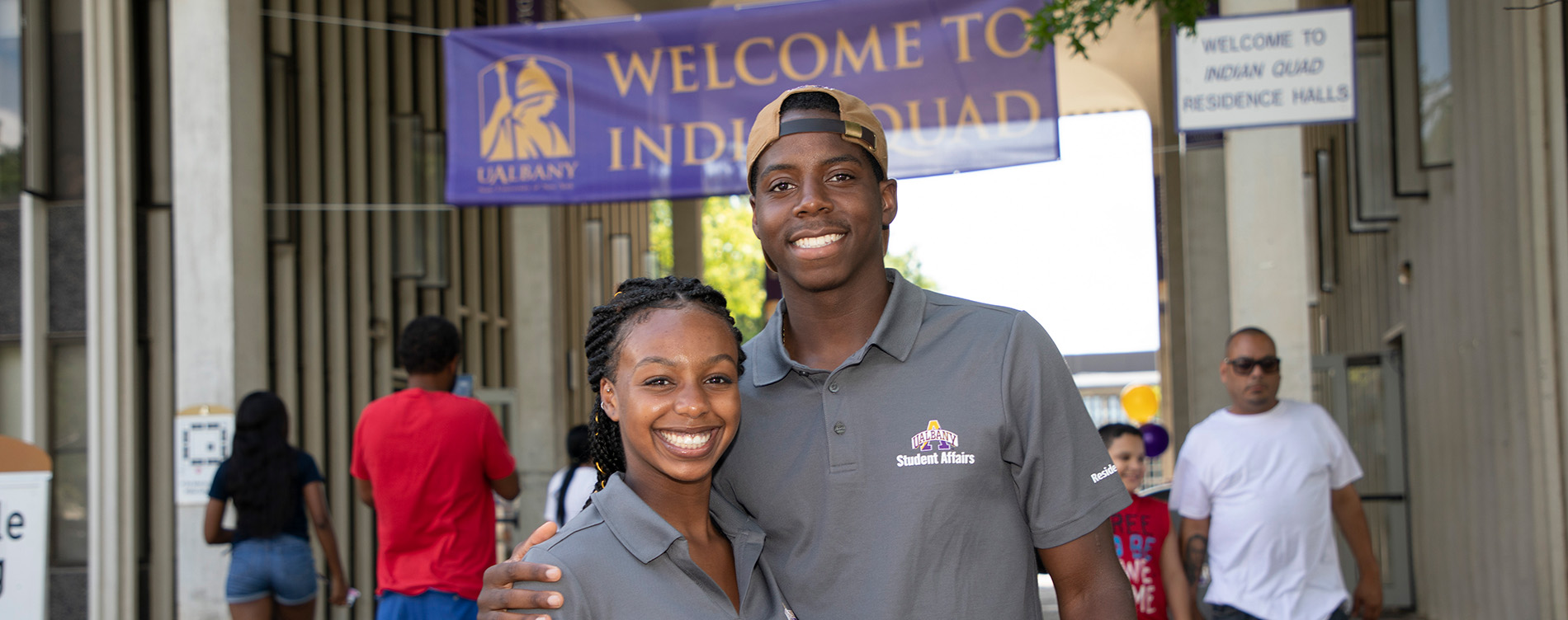Two Resident Assistants pose for a photo outside Indigenous Quad on move-in-day