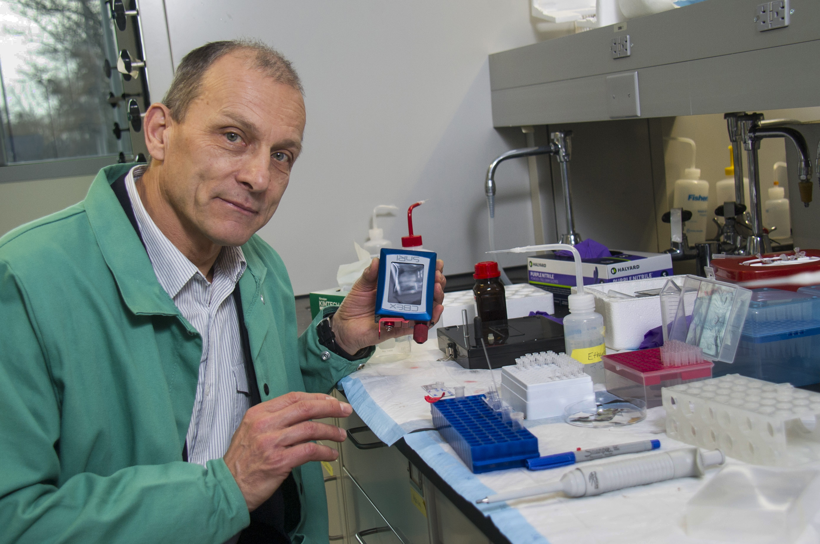 Igor Lednev holds a portable instrument in his lab space.