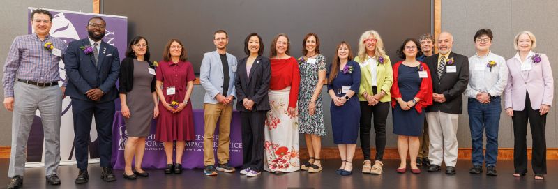 15 smiling people wearing name tags stand in a row.