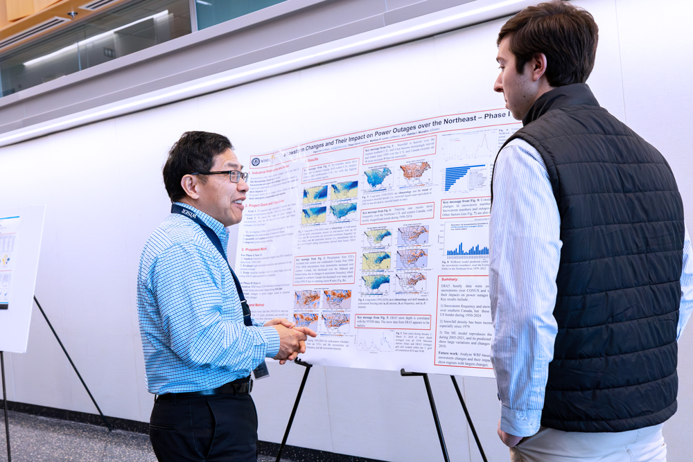 Two people have a discussion in front of a research poster presentation.
