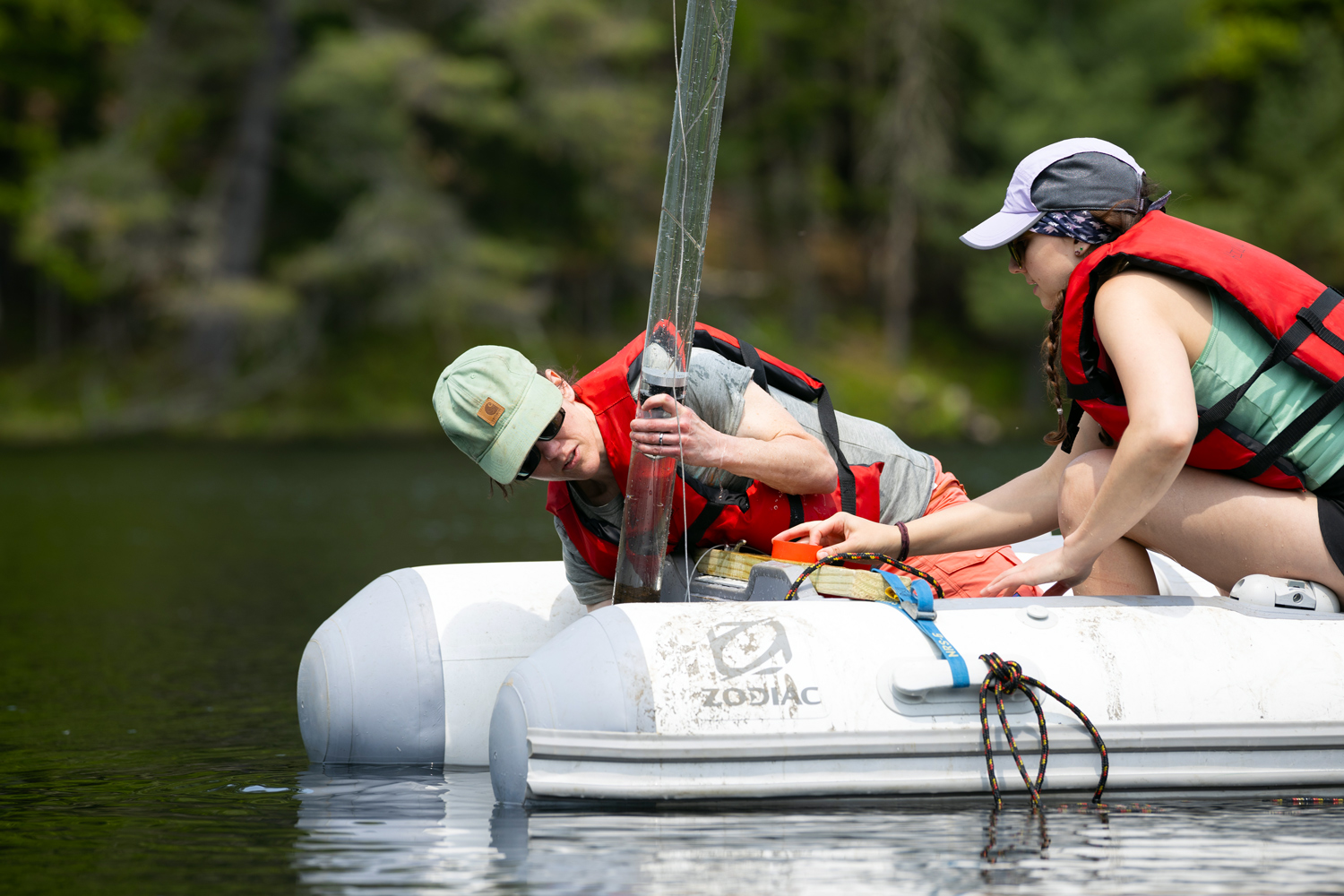 Two students conducting environmental research in a boat on a lake.
