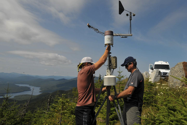 University at Albany undergraduate student Matthew Brewer (left) sets up a weather station with Whiteface Mountain Site Operations Manager Paul Casson at the Lake Placid Turn along the road to the peak of Whiteface Mountain in the Adirondacks.