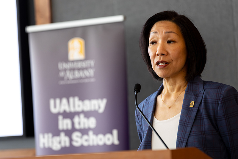 UAlbany Provost and Senior Vice President Carol Kim speaks at a podium with a sign behind her that says "UAlbany in the High School"