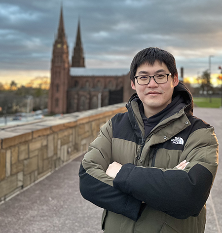 UAlbany student Tzuhao Chen stands outside in Albany NY with the Cathedral in the background.