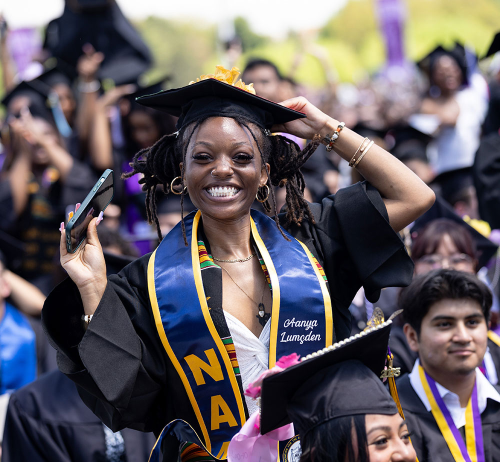 Student standing and smiling at commencement in full regalia