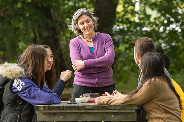 Faculty teaching a small class outside at a table.